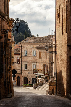 View of the historic brick architecture and narrow cobblestone streets of the old town under a cloudy sky in Ripatransone, Marche, Italy.
