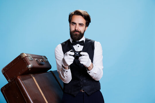 Doorkeeper posing with controller and playing videogames on the internet, feeling happy with gaming challenge in studio. Porter with suit and gloves has fun on camera, playing game.