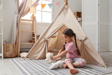 Little girl playing with toys near toy wigwam in playroom © New Africa