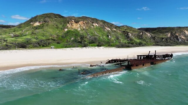 Aerial drone view of SS Maheno shipwreck on Fraser Island K'gari, Queensland, Australia. Rusting wreck on white sand beach with turquoise water, iconic coastal travel destination.