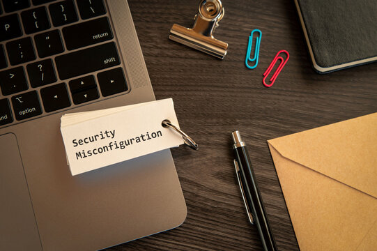 Secure technology and Security Misconfiguration on word card with laptop, clips, pen. Cyber security, protection and digital trust.
