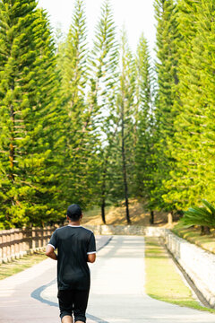 a man jogging along a paved path in Taman Saujana Hijau, a popular 41-hectare recreational park located in Putrajaya, Malaysia