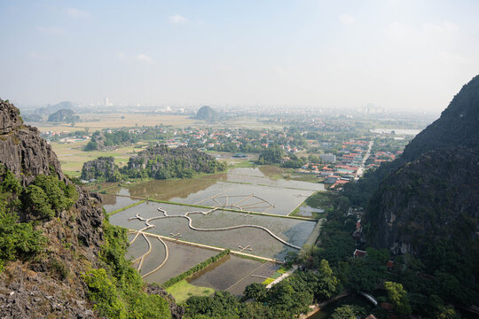  panoramic wide-angle shot overlooking a network of flooded rice fields and winding dirt paths in the Tam Coc region