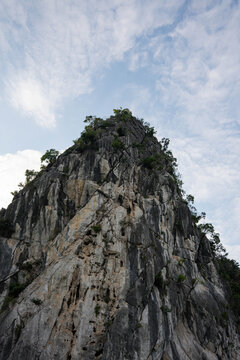 a majestic limestone cliff face under a blue sky, characterized by sparse vegetation and a rugged, weathered texture