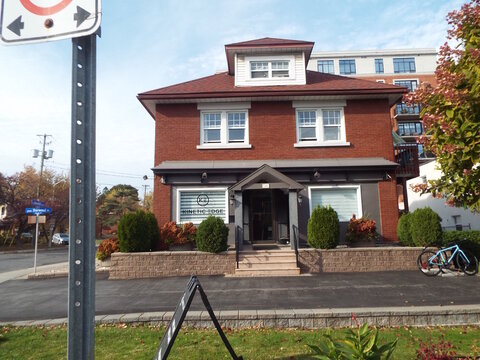 Ottawa, Ontario, Canada &ndash; August 02, 2025: A brick building housing "Kinetic Edge" features a front entrance with signage, landscaping, and a bicycle parked outside at  917 Carling Ave.