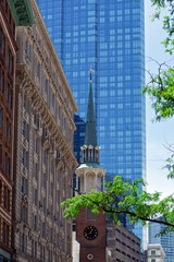 Obraz premium Historic Old South Meeting House steeple standing tall against a modern blue glass skyscraper in Boston, Massachusetts, USA 