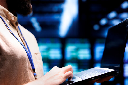 Close up shot of technician inspecting crypto mining server rigs solving complex mathematical equations. Specialist using laptop in data center housing blockchain technology high volume transactions