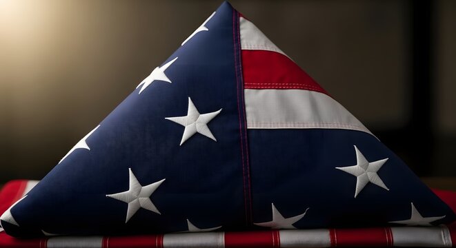 A close-up shot of a folded American flag. The flag is meticulously folded into a triangular shape, showcasing its stars and stripes