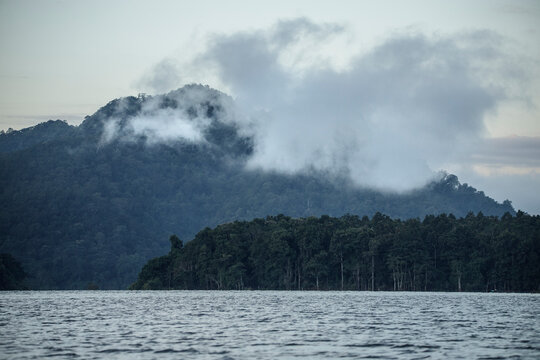 Serene landscape of mountains and a lake under early morning fog.