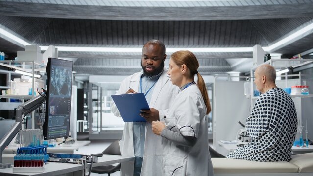Medical researchers performing a clinical evaluation of a patient in a laboratory drug study, testing treatment safety and pharmacology outcomes to drive progress in healthcare. Camera A.