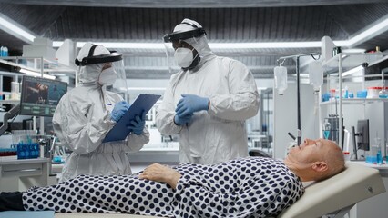 Healthcare professional in hazmat suit performs diagnostics on a patient infected with dangerous...