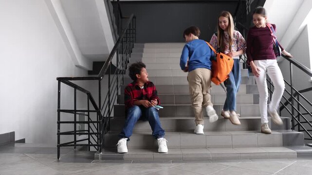 African American boy getting bullied by his classmates on stairs in school