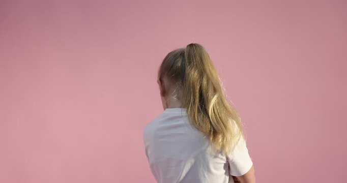 Resentful little girl posing on pink background
