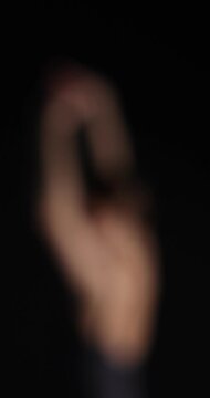 Graceful ballerina practicing dance moves on black background