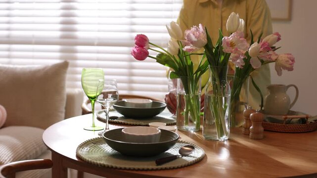 Woman setting table for dinner in dining room, closeup. Camera moving forward