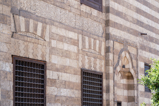 View of the intricate Mamluk architecture of Al Ghuri Dome featuring ablaq masonry, Arabic calligraphy, and ornate window grilles, Cairo, Egypt.