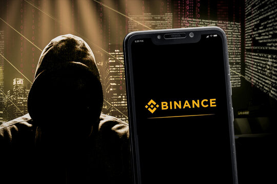 Cali, Colombia - May 13 2022: Phone displaying Binance logo against hooded hacker silhouette. Binance is a cryptocurrency exchange.