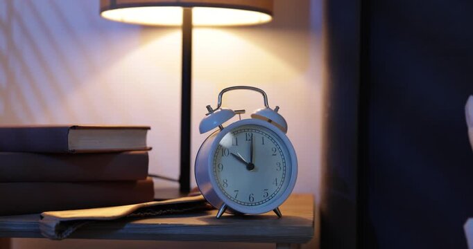 Woman stopping alarm clock at bedside table indoors, closeup