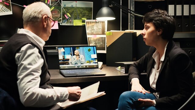 Law officers on videocall with director sharing new crucial case information, attending briefing telework call in incident room. Police team discussing about proof with commissary. Handheld shot.