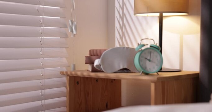 Alarm clock ringing on bedside table indoors. Camera moving right