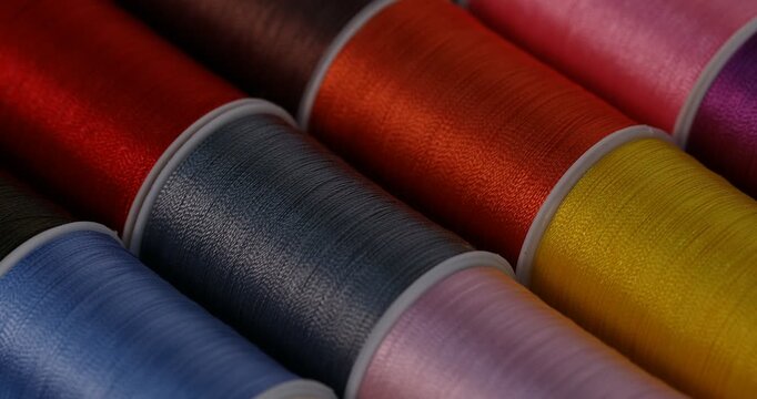 Spools of sewing threads as background, closeup. Changing direction of light