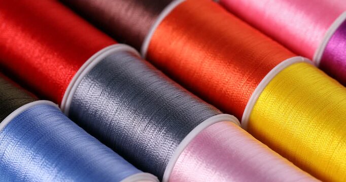 Spools of sewing threads as background, closeup. Changing direction of light