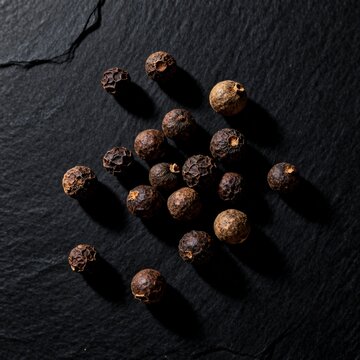 Heap of whole peppercorns and mixed spices on dark slate background