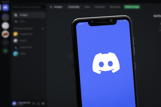 Cali, Colombia - April 20 2022: Smartphone displaying Discord logo against a blurred desktop application interface.