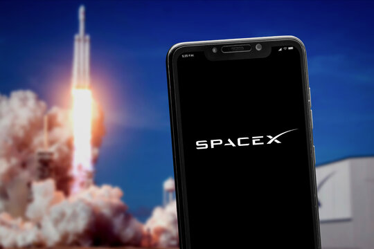 Cali, Colombia - May 6 2022: "SpaceX" logo on the smartphone screen and launch of a rocket at the blurred background. SpaceX is a space transportation and aerospace manufacturer.