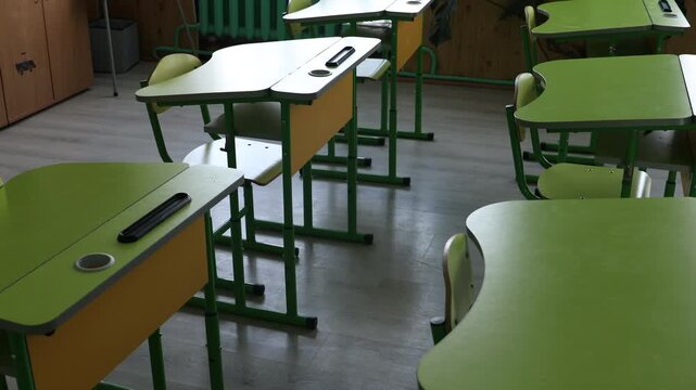 Green desks and chairs in classroom at school. Camera moving left