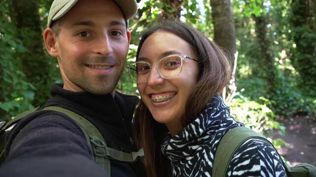 Happy hiking couple taking selfie in forest