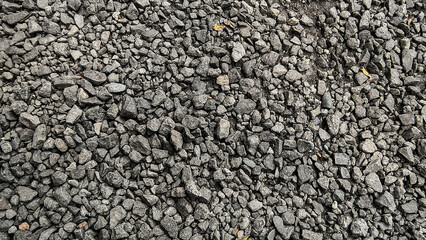 Obraz premium A detailed, close-up, overhead view of a textured surface covered in small, dark gray, angular gravel stones