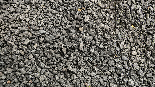 A detailed, close-up, overhead view of a textured surface covered in small, dark gray, angular gravel stones