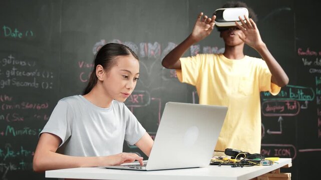 African boy wear headset to enter in metaverse while young beautiful academic student writing, coding, programming system on table with laptop or device placed. innovative education. Edification