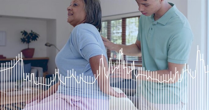 Supporting senior woman in blue top on sofa at home, caregiver in mint-polo placing hands, waveform