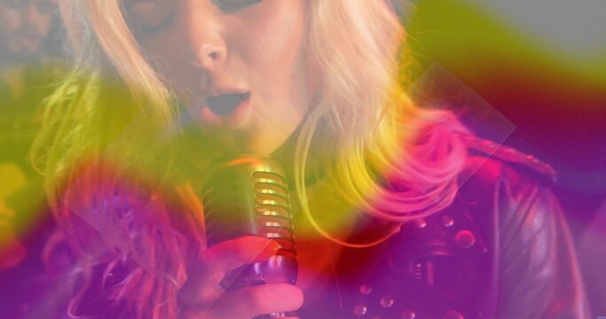 Singing female vocalist holding retro chrome mic in studio with studded jacket and haze