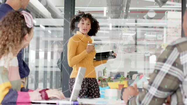 Presenter entering business meeting, tapping tablet and activating circular UI while guiding team