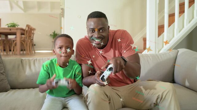 Father and son playing tech game on couch, pressing white controllers activating sparkles overlay