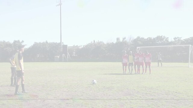 Soccer attacker taking run-up and striking ball toward goal, aiming to score, defenders reacting