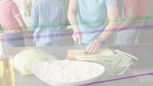Man placing cutting board and chopping green onions on island, preparing meal, scanlines overlaying