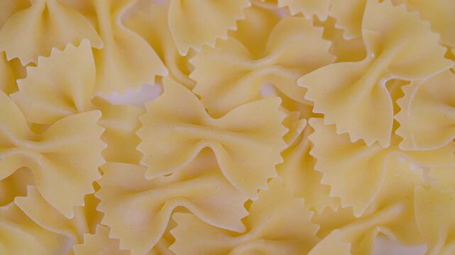 Pasta detailed closeup. Zoomedin image showcasing intricate details of dry bowtie pasta. Studio shot capturing detailed texture and form of dry goldcolored bowtie pasta
