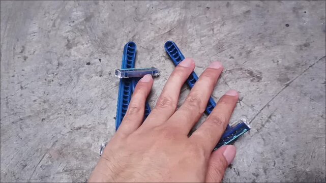 Top view of old used blue plastic disposable razors scattered on a grey concrete surface