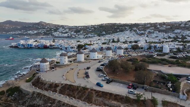 Drone shot of windmills of Mykonos on Greek Island surrounded by blue ocean and hills, Cyclades island