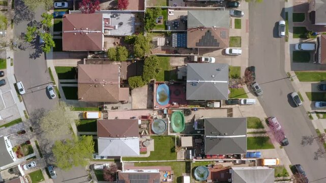 bird's-eye view panning across a dense American residential block. The footage captures colorful rooftops, backyard pools, and quiet suburban streets in the North East United States