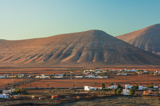 View of volcanic mountains and a small village with white houses under a clear sky during sunset Lanzarote, Canarias, Spain.
