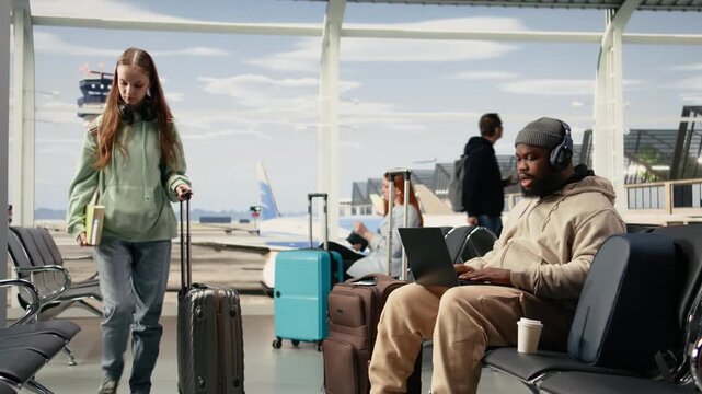 African american man on video conference call using airport internet, speaking to colleagues during online meeting while seated in the terminal waiting area. Digital communication and mobility.