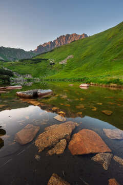 View of Bystre pleso lake in the Low Tatras National Park with clear water reflecting green mountain slopes and rocky peaks Liptovsky Mikulas, Zilinsky kraj, Slovakia.