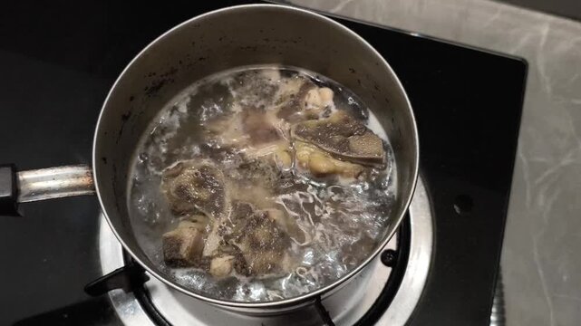 Beef bone soup boiling in a pot on gas stove
