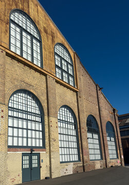 Industrial brick building facade with large arched windows and repeating architectural pattern, showcasing urban design, texture, and perspective in modern adaptive reuse