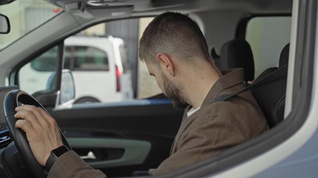 Man reaches to adjust rearview mirror with hand while wearing seatbelt in car on street; concentration.